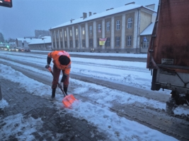 Na zdjęciu mężczyzna z MPGK odśnieżający łopatą przystanek