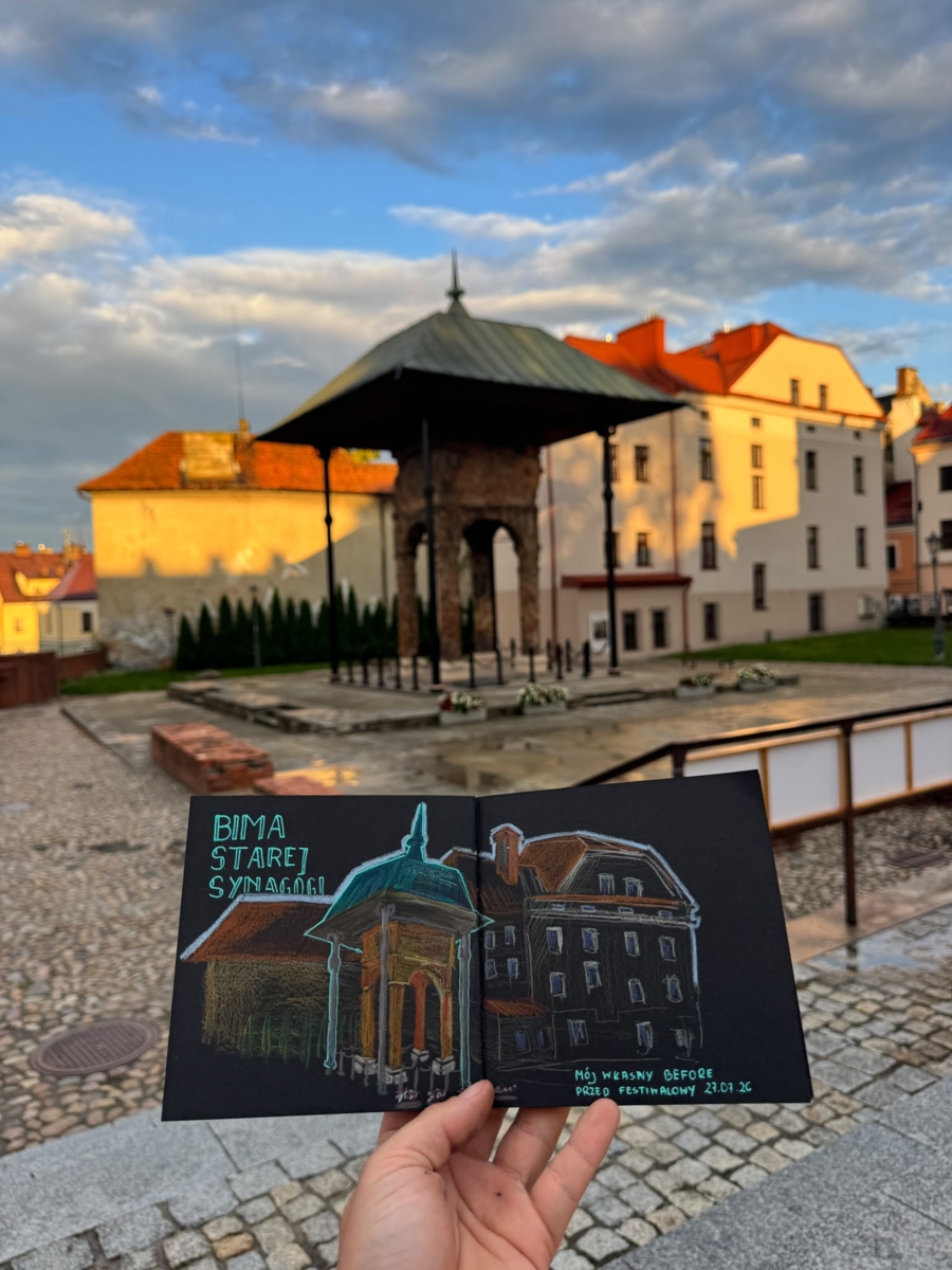 na zdjęciu szkic bimy na czarnym papierze, trzymany w ręce, w tle tarnowska bima