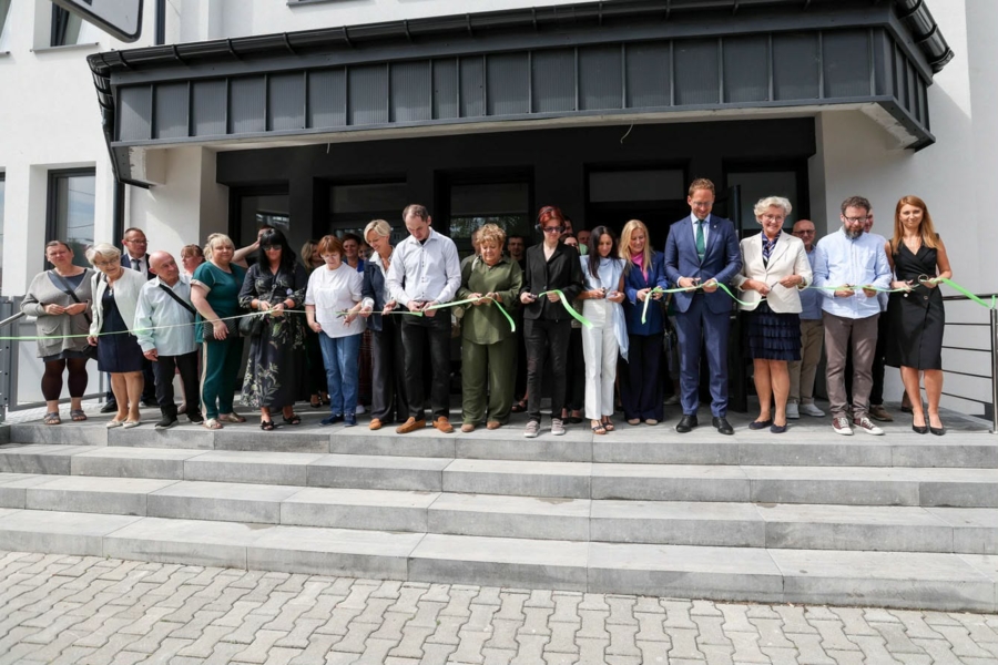Zdjęcie z oficialnego otwarcia, uczestnicy stoją przed budynkiem i przecinają wstęgę