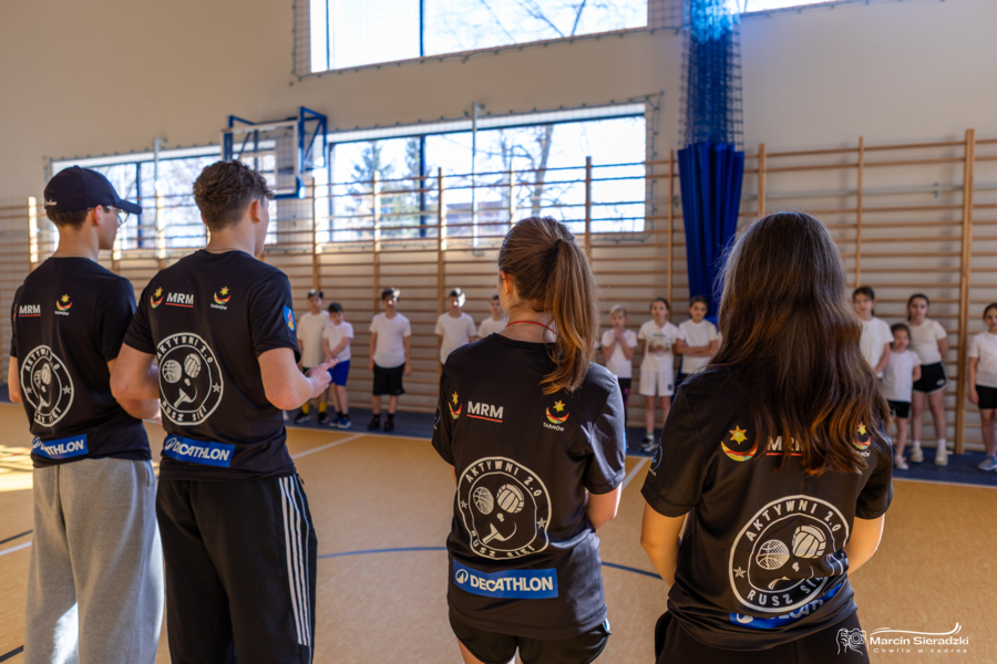 na zdjęciu uczestnicy akcji którzy rozmawiają z dziećmi przebranymi w stroje do WF-u